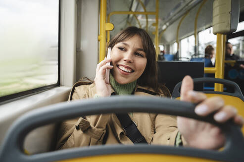 Glücklicher Fahrgast, der im Bus mit seinem Handy telefoniert - ALKF01143