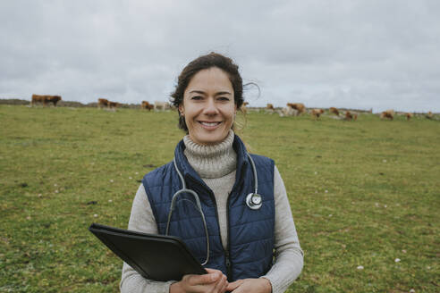 Lächelnder Tierarzt mit Stethoskop auf dem Bauernhof - DMGF01313