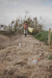 Woman collecting bottles at countryside - DMGF01323