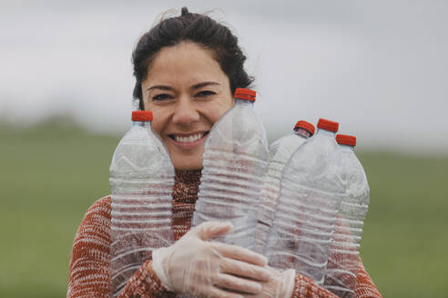 Happy volunteer holding plastic bottles at countryside - DMGF01328