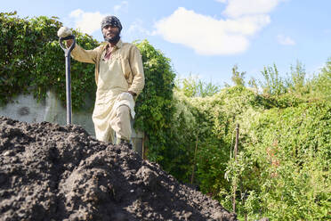 Gärtner gräbt Erde für die Bepflanzung im Garten an einem sonnigen Tag - DSHF01683