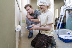 Vater lehrt Junge, die Wand zu Hause zu streichen - NJAF00939