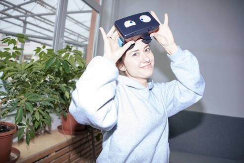 Lächelnde Frau trägt Virtual-Reality-Headset zu Hause - KNSF10252