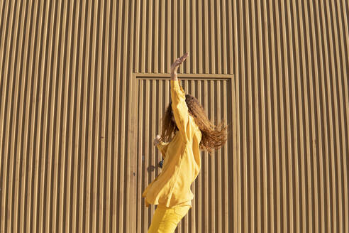 Black girl with curly hair dressed in yellow pants and shirt, posing jumping. Granada, Spain. - MGRF01161