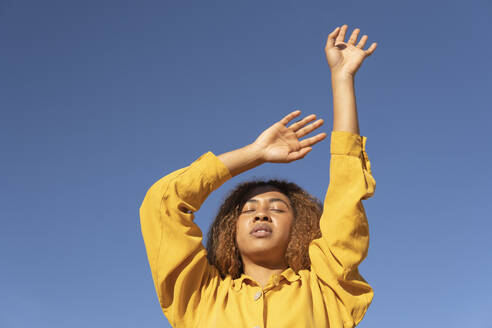 Close-up of a curly-haired black girl dressed in yellow pants and shirt, posing very relaxed. Granada, Spain. - MGRF01183