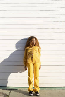 Portrait of a curly-haired black girl dressed in yellow pants and shirt, posing aesthetically with hearts on her cheeks. Granada, Spain. - MGRF01200