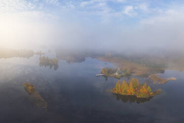 Luftaufnahme einer nebligen Landschaft zur goldenen Stunde über einem nebligen Wald, Karelien, Russland. - AAEF28198