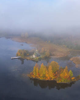 Aerial view of Skorbyashchenskaya Church with foggy autumn forest on an island in Karelia, Russia. - AAEF28199