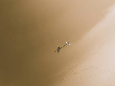 Luftaufnahme eines Surfers und seines Schattens an einem goldenen Strand in Peniche, Portugal. - AAEF28449