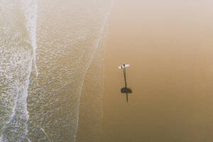 Luftaufnahme eines Surfers und seines Schattens an einem goldenen Strand in Peniche, Portugal. - AAEF28451