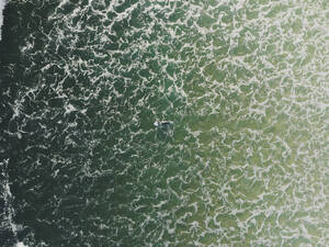 Luftaufnahme eines Surfers, der in den Wellen des Ozeans in Peniche, Portugal, schwimmt. - AAEF28452
