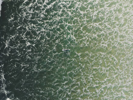 Luftaufnahme eines Surfers, der in den Wellen des Ozeans in Peniche, Portugal, schwimmt. - AAEF28452
