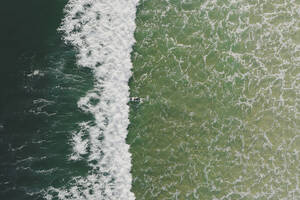 Luftaufnahme eines Surfers, der in den Wellen des Ozeans in Peniche, Portugal, schwimmt. - AAEF28453