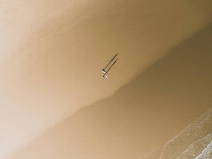 Luftaufnahme von zwei Surfern und ihrem Schatten an einem goldenen Strand in Peniche, Portugal. - AAEF28454