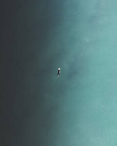 Luftaufnahme eines Surfers beim Schwimmen im blauen Meer in Peniche, Portugal. - AAEF28458