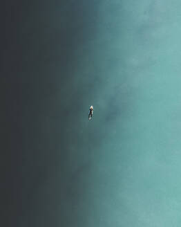 Luftaufnahme eines Surfers beim Schwimmen im blauen Meer in Peniche, Portugal. - AAEF28458