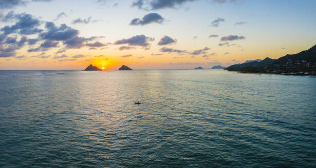 Aerial view of a kayaker watching the sunrise between the Mokulua Islands that lie off Lanikai Beach, Kailua Bay, Oahu, Hawaii, United States. - AAEF28545