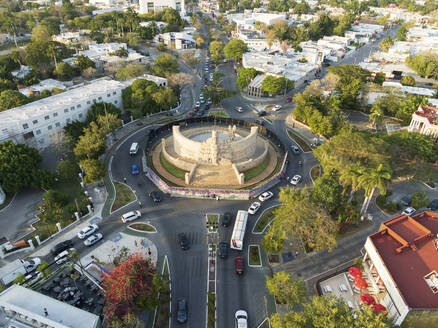 Luftaufnahme des Paseo de Montejo, Kreisverkehr Monumento a la Bandera mit Verkehr, Bäumen und Schatten am Abend, Merida, Yucatan, Mexiko. - AAEF28555