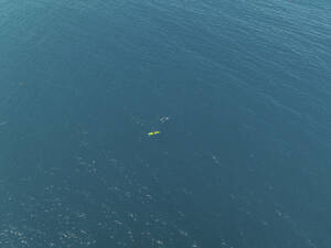 Aerial view of a two tiny people canoeing into the sea in Milazzo, Sicily, Italy. - AAEF28646