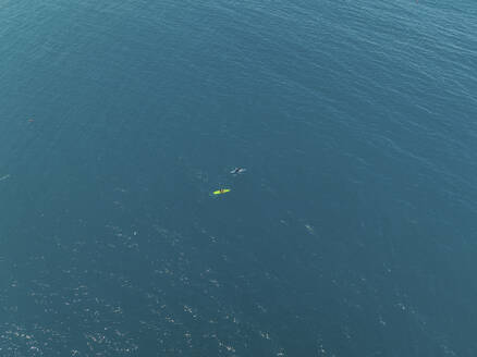 Aerial view of a two tiny people canoeing into the sea in Milazzo, Sicily, Italy. - AAEF28646