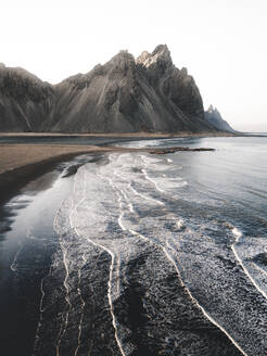 Aerial view of waves crashing onto the beach in front of Vestrahorn mountain, Stokksnes, Iceland. - AAEF28773