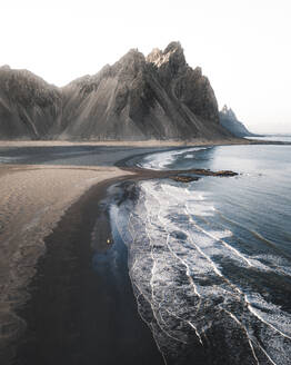 Aerial view of a person standing on a beach in front of Vestrahorn mountain, Stokksnes, Iceland. - AAEF28774