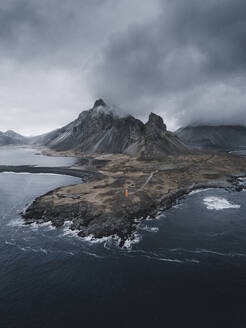 Aerial view of a lighthouse standing in front of Eystrahorn mountain, Hvalnes Nature reserve, Austurland, Iceland. - AAEF28779