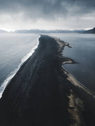 Aerial view of a black sand beach stretching along the coast in Hvalnes Nature reserve, Austurland, Iceland. - AAEF28781