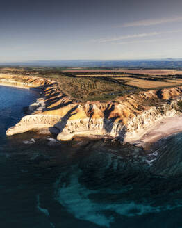 Luftaufnahme von zerklüfteten Kalksteinklippen mit einem türkisblauen Meer im Vordergrund und einem weißen Sandstrand, Port Willunga, Südaustralien, Australien. - AAEF29040