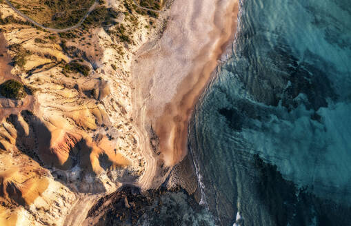 Aerial view of limestone cliffs with a sunset hue and blue coastal water from above, Port Willunga, South Australia, Australia. - AAEF29043