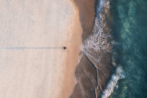 Luftaufnahme eines Fotografen am Strand von oben mit blauem Meerwasser und Langzeitbelichtungseffekt auf den Wellen, Port Noarlunga, South Australia, Australien. - AAEF29048