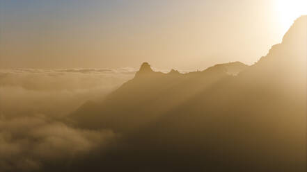 Drohnenaufnahme der Silhouette von Berggipfeln bei Sonnenaufgang, bedeckt von Wolken, Insel Santo Antao, Kap Verde. - AAEF29126