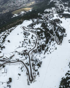 Luftaufnahme einer gefrorenen Winterlandschaft mit kurvenreicher Straße durch verschneite Berge, Monte Boldone, Vason, Trentino, Italien. - AAEF29213