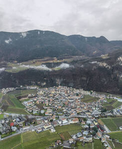 Luftaufnahme des Dorfes Salorno, umgeben von Bergen, Hügeln und Nebel, Südtirol, Italien. - AAEF29224