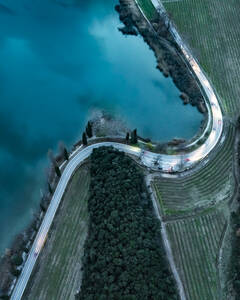 Luftaufnahme des Toblino-Sees mit kurvenreicher Straße und umliegenden Bergen, Madruzzo, Trentino, Italien. - AAEF29286