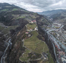 Aerial view of Sabiona Monastery and Chiusa town with winding roads and terraced vineyards, Klausen, South Tyrol, Italy. - AAEF29322