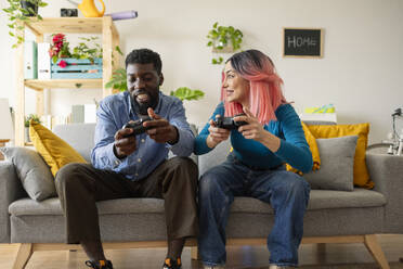 Glückliche Freunde spielen ein Videospiel auf dem Sofa zu Hause - JCCMF11598