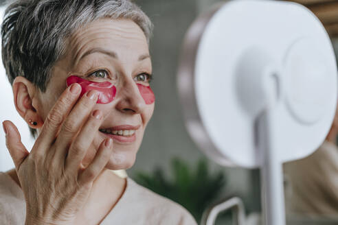 Ältere Frau, die zu Hause eine Augenmaske aufträgt - YTF02136