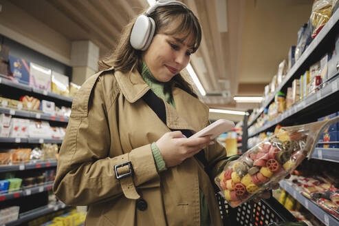 Woman using smart phone to check information of product at supermarket - ALKF01152