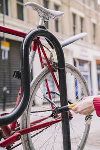 Hand einer Frau, die ihr Fahrrad an einer Parkstation abschließt - AMWF02101