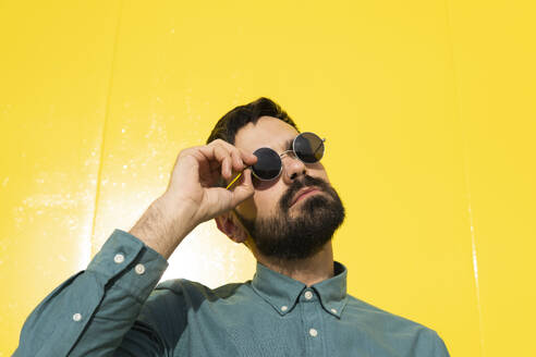 Mann mit Sonnenbrille vor einer gelben Wand - MGRF01288