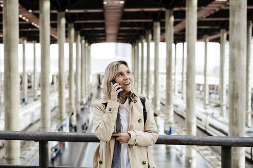 Frau spricht am Bahnhof mit einem Smartphone - EBBF08836