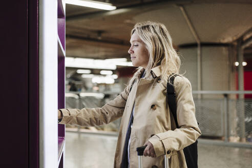 Frau benutzt einen Fahrkartenautomaten im Bahnhof - EBBF08857