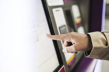 Frau berührt den Bildschirm eines Fahrkartenautomaten am Bahnhof - EBBF08858