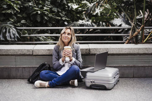 woman at train station working on laptop, Madrid, Spain - EBBF08874