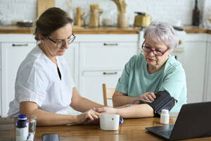 Krankenschwester misst Blutdruck einer älteren Frau zu Hause - DMBF00038