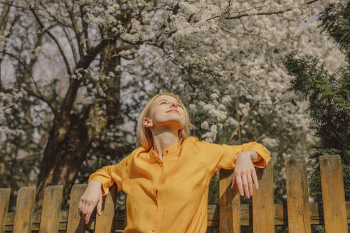 Lächelnde Frau unter weiß blühendem Baum an einem sonnigen Tag - VSNF01808