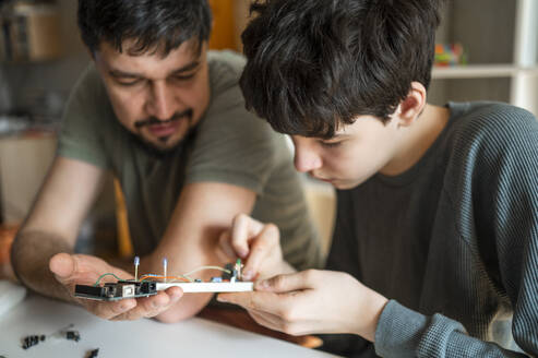 Vater hilft Sohn bei der Reparatur von Elektrogeräten zu Hause - ANAF02819