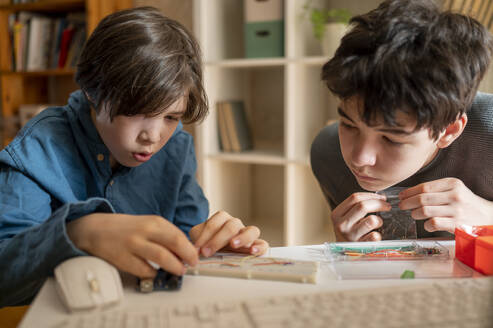 Junge stellt Mikrocontroller in der Nähe seines Bruders zu Hause ein - ANAF02826