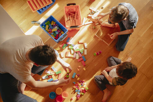 A father and his children play with toys at home. Dad spends time with his sons - ANAF02830